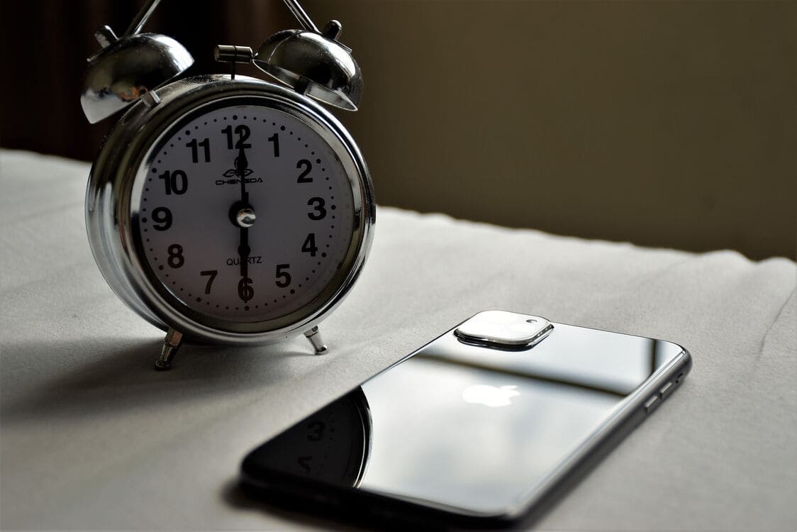 A phone face-down on a bedside table, playing calm audio-only bedtime stories in a dim room.